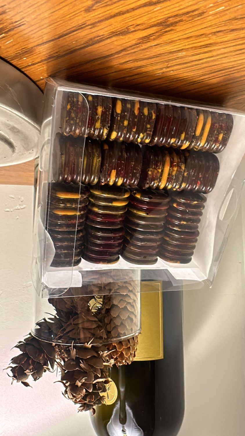 A clear gift box of Cioccoland marbled chocolate discs in gold, red and dark tones